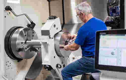 CNC-Drehen auf DMG NLX Drehmaschine – Mitarbeiter misst Präzisionsbauteil in der Lohnfertigung
