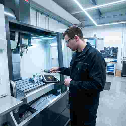 Moderne CNC-Fräse, Techniker mit Messschieber und Tablet mit abstrakten Diagrammen; Präzision.