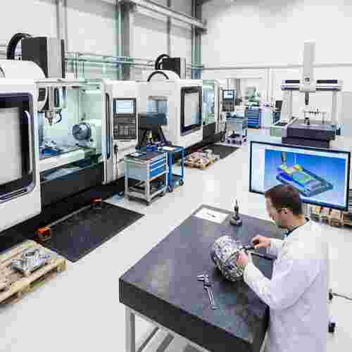 Moderne CNC-Fertigung: 3–5 Achsen, Techniker prüft Präzisionsbauteile, CAD/CAM-Display, CMM.