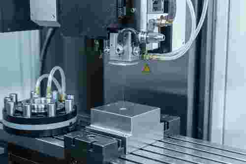 Moderne Drahterodiermaschine beim Erzeugen winzigen Startlöchern Kühlung sichtbar