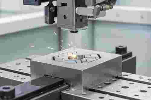 Nahaufnahme einer Drahterodiermaschine beim Schneiden eines Metallteils in einer modernen Fertigungshalle; Funken, Dielektrikum.