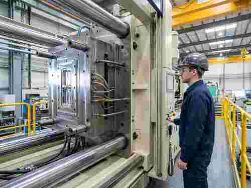 Große Stahlform in der Presse, glänzende Oberflächen, Techniker, unscharfer Hintergrund.