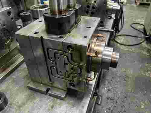 Nahaufnahme einer Extrusionsdüse und Werkzeugbaugruppe aus Stahl mit Carbid-Komponenten und Kühlkanälen.