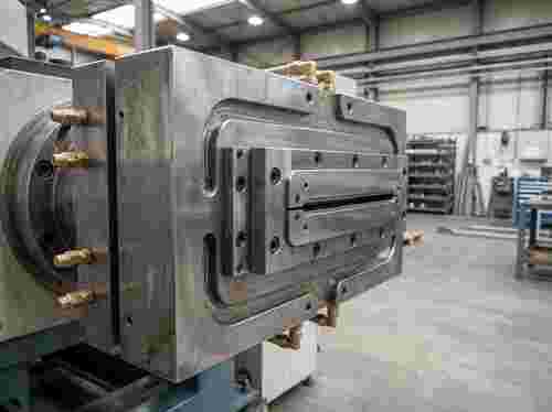 Nahaufnahme eines Kunststoff-Extrusionswerkzeugs mit Düse, Metallkörper und Kühlkanälen