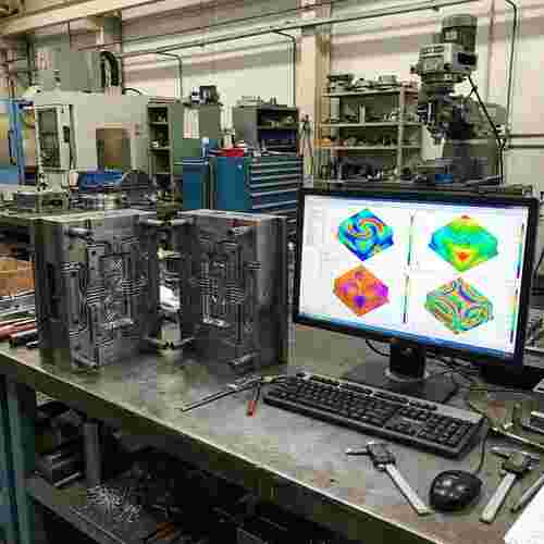 Spritzgießformenhälften mit Kühlkanälen, CAD/CAM-Werkstatt, Monitor mit CAE-Überlagerungen.