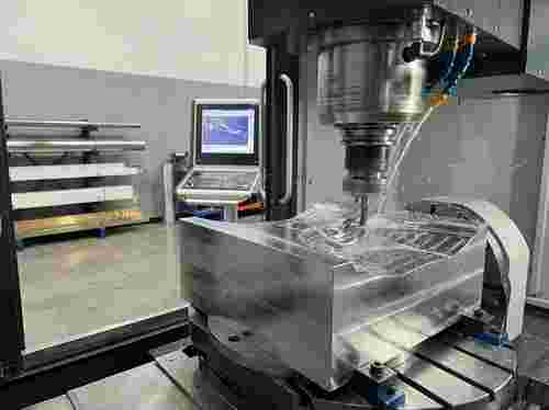 5-Achs-CNC-Fräsmaschine bearbeitet Aluminiumblock; makellose Oberflächen, CAM/CAD im Hintergrund