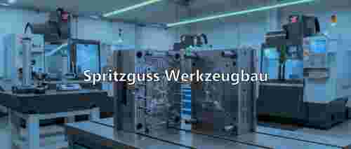 Eine Spritzgussform, die symbolisch für den Spritzguss Werkzeugbau mit Werkzeugtechnik Schmitz steht. Sie ist aus Metall und steht auf einem Tisch, alles sieht sehr steril aus. Im Hintergrund sind weitere Spritzgussmaschinen zu sehen, in grau, weiß und mit Glas. Die Wände sind weiß und an der Decke leuchten Röhrlichter.