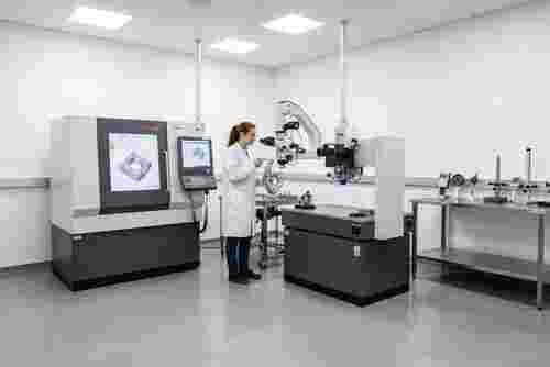 Techniker prüft komplexe Metallteile in moderner Wire-EDM-Qualitätssicherung; Toleranz 0,001 mm, CMM.