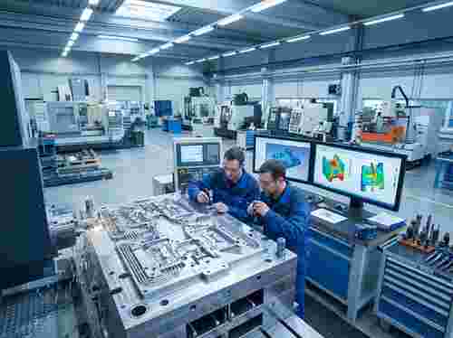 Hochpräzises Spritzgießwerkzeug in moderner Fertigung; CAD-Modelle sichtbar.