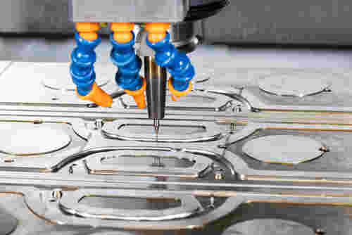 Fräsvorgang eines Spritzguss-Werkzeuges von Werkzeugtechnik Schmitz. Das Fräswerkzeug wird umgeben von vlauen Drähten mit orangenen Ausgängen.